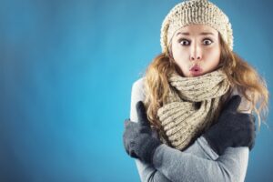 woman-wearing-scarf-gloves-hat-looks-cold-and-astonished-against-blue-background